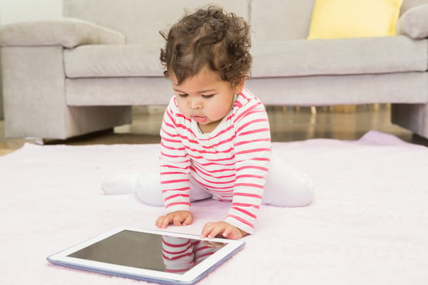 Cute baby on the carpet with tablet at home